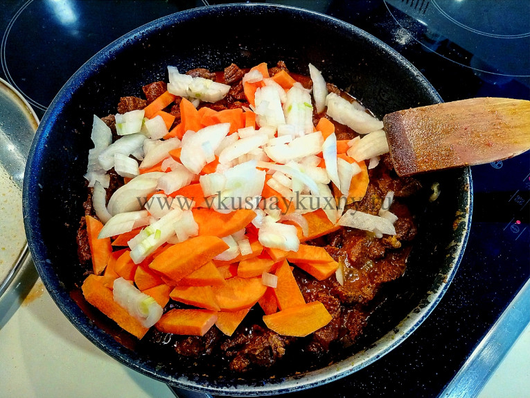 Добавляем лук с морковью к мясу в сковороду и тушим