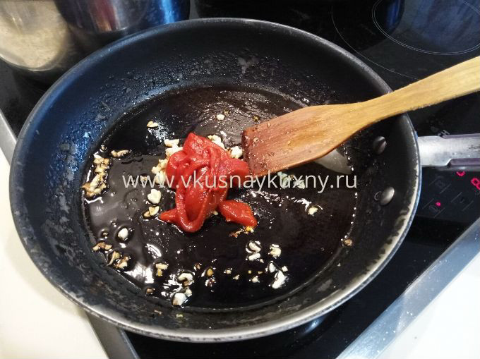 Добавляем томатную пасту к чесноку на сковороде