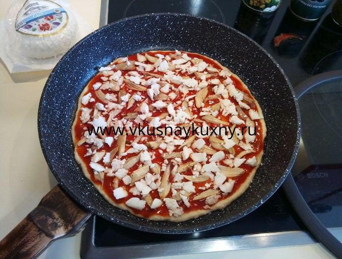 Раскладываем кусочки сыра поверх томатного соуса для пиццы равномерно