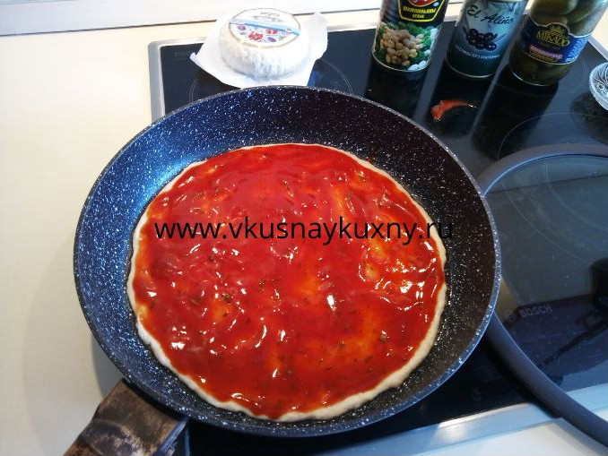 Смазанное тесто для пиццы томатным соусом ровным слоем